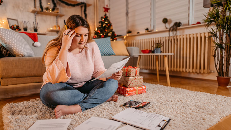 Woman sitting in holiday-decorated living room, looking stressed out.