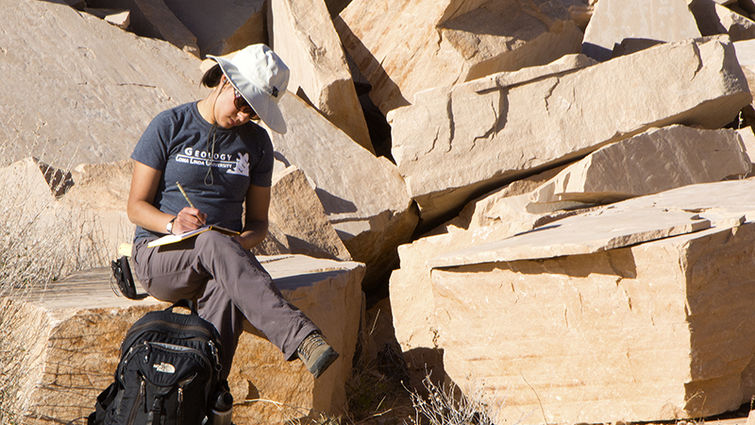 Sarah Maithel annotates her findings while sitting on a slab of Coconino Sandstone