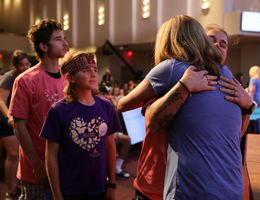 A FAMILY EMBRACES A VOLUNTEER WITH A HUG DURING MEMORIAL SERVICE FOR LOST BABIES AND INFANTS