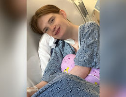 Emily Conant looks at camera while lying in hospital bed