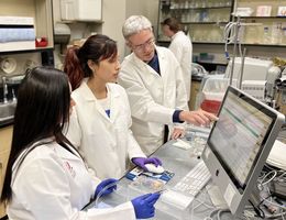 Dr. Arlin Blood conducts research with two students.