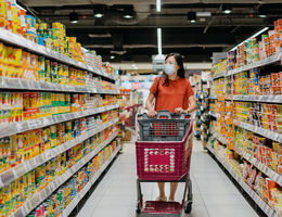 Woman shopping in supermarket aisle lined with processed foods