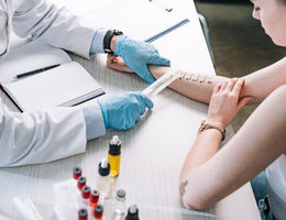 overhead view of allergist holding ruler near marked hand of woman