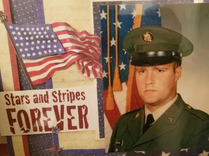 a man in an army uniform poses in front of the American flag