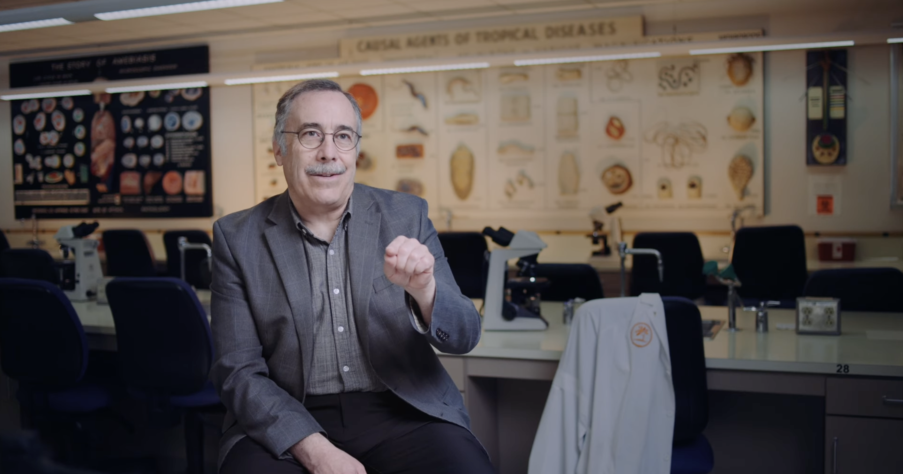 a man is sitting in front of a research medical lab and pointing