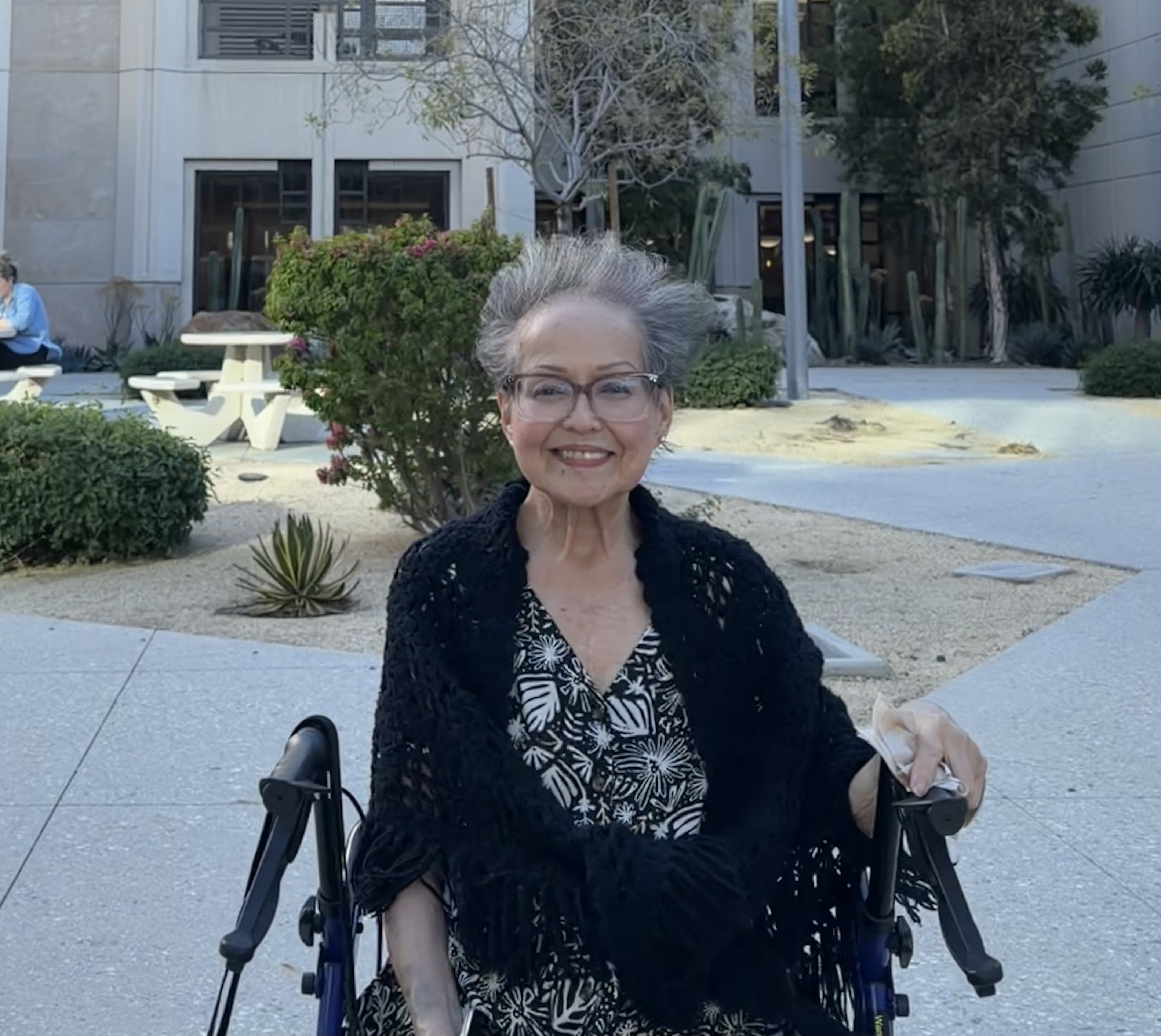 a woman sits and poses in front of a white building 