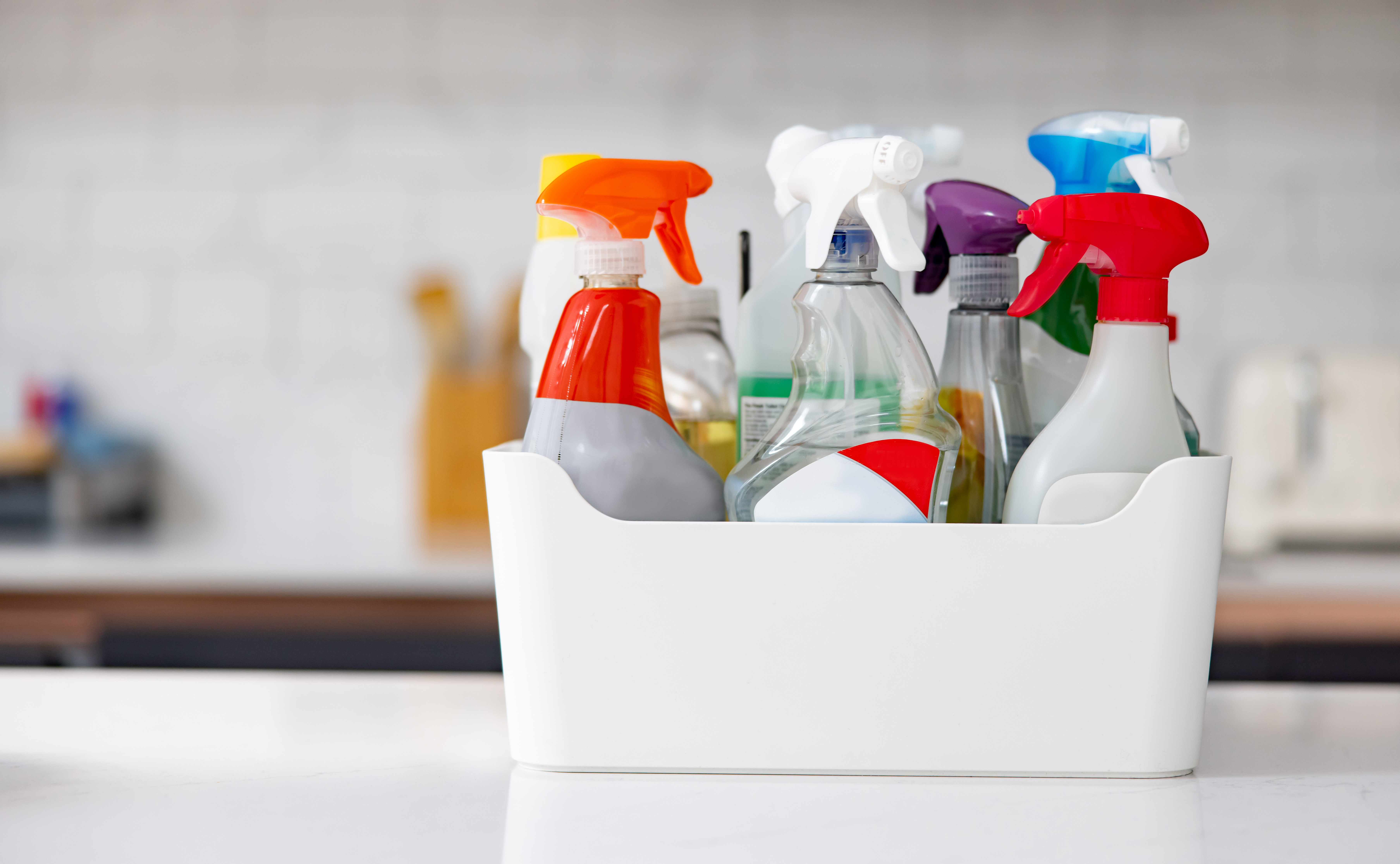 Box with cleaning products on the kitchen counter at home 