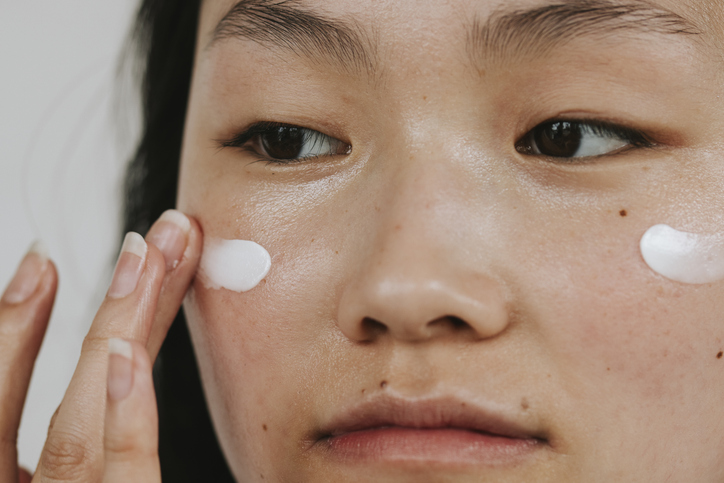Woman putting face cream on
