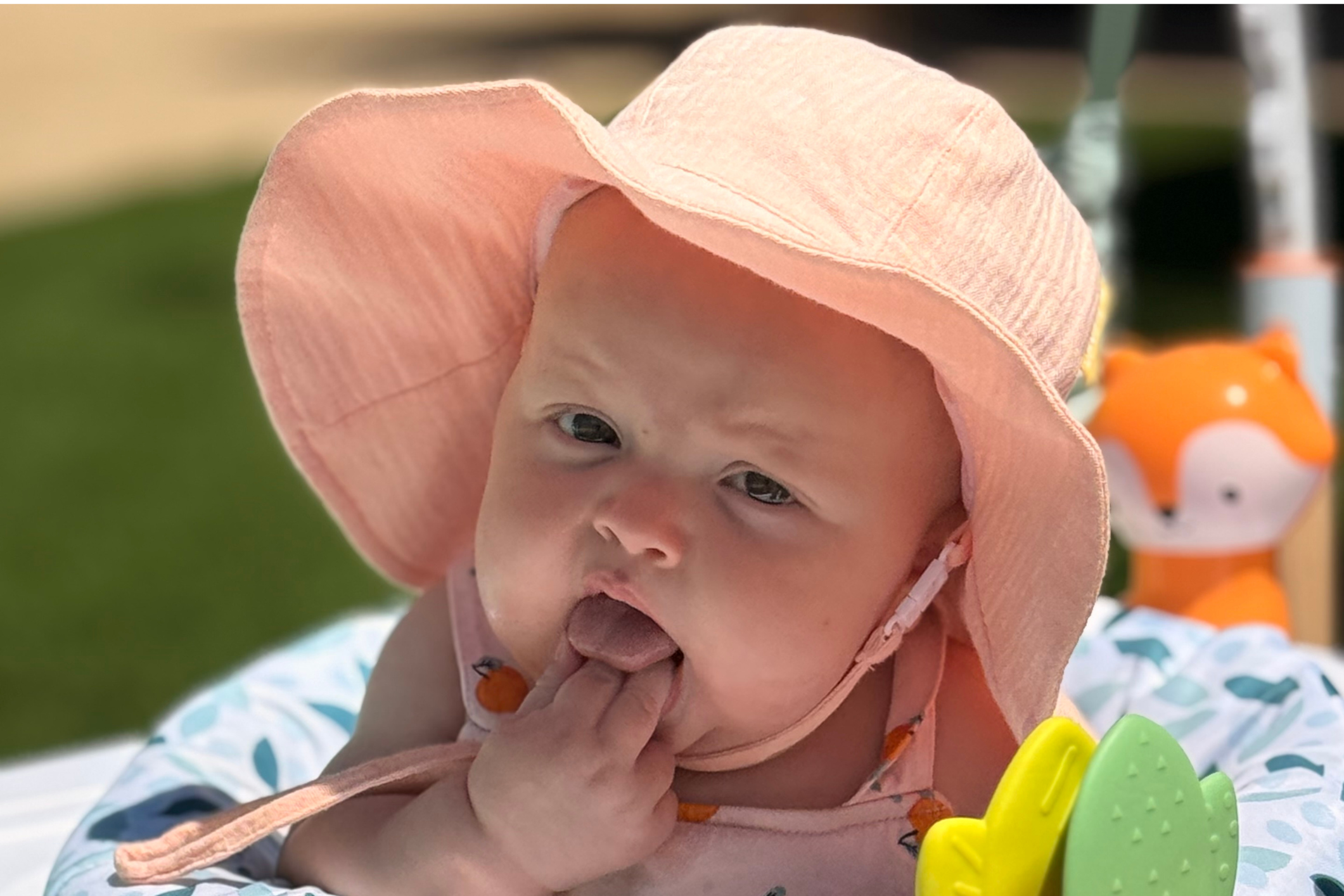 Baby wearing sunhat sitting in rocker outdoors
