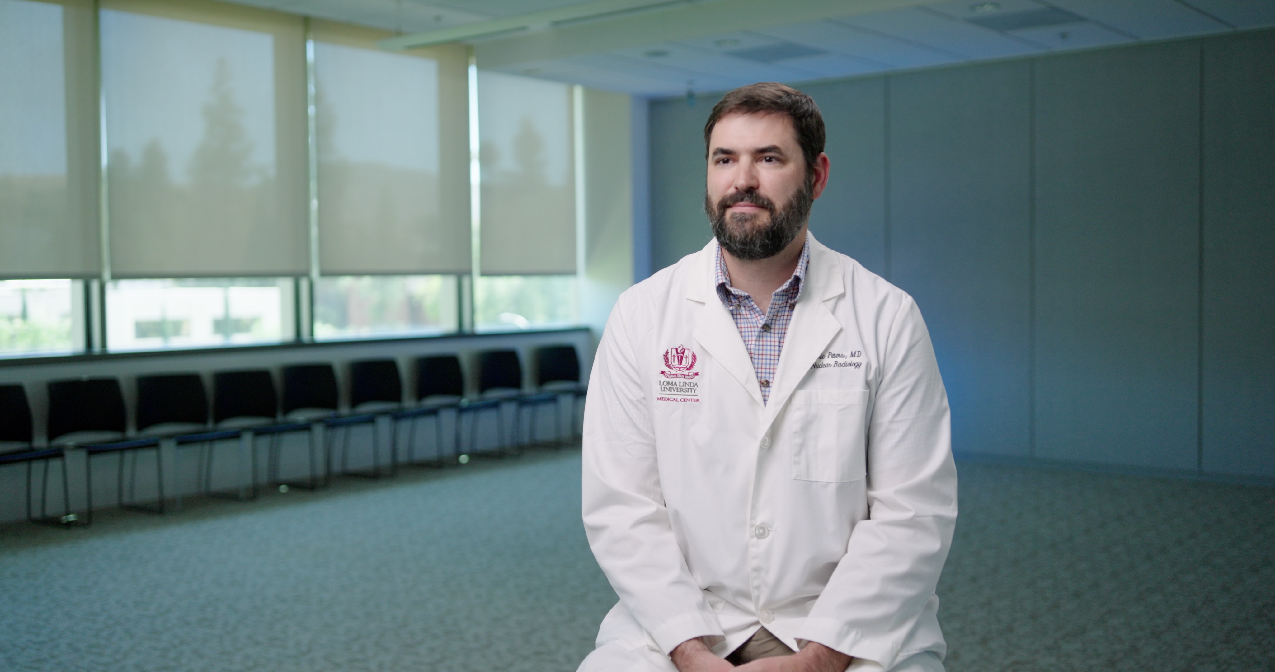 Dr Peters speaking while sitting in an empty room