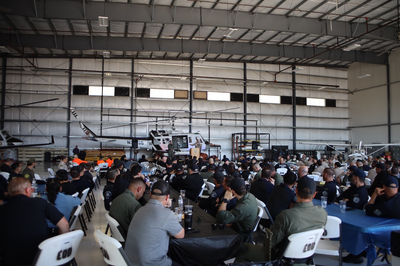 Law enforcement officers listen to remarks at hangar.