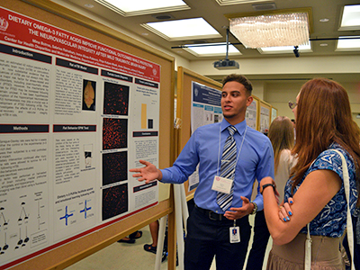 Mino Botros, left, shares his poster with a symposium attendee.