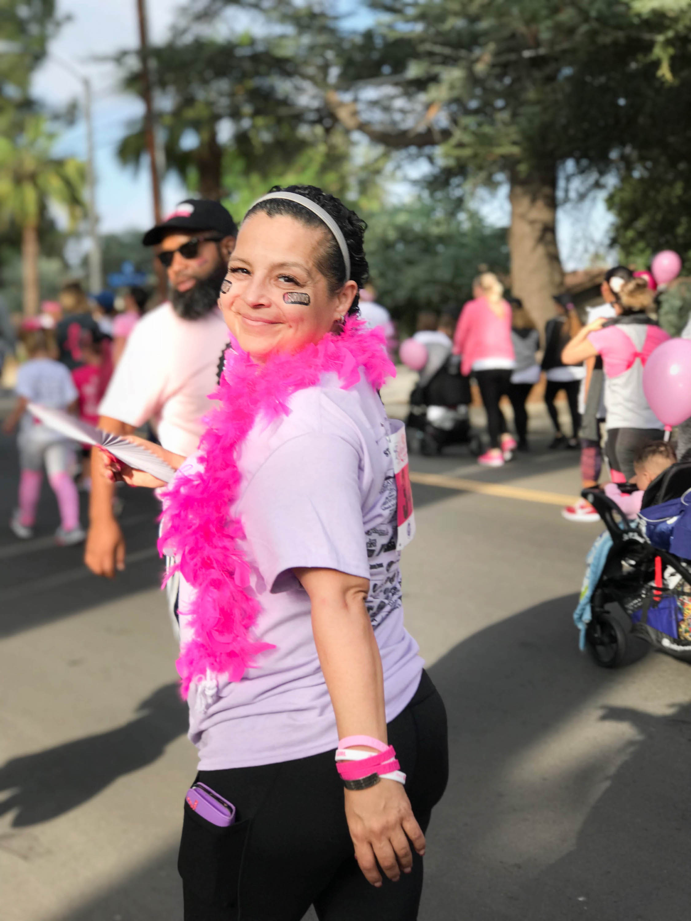 woman stands in pink boa