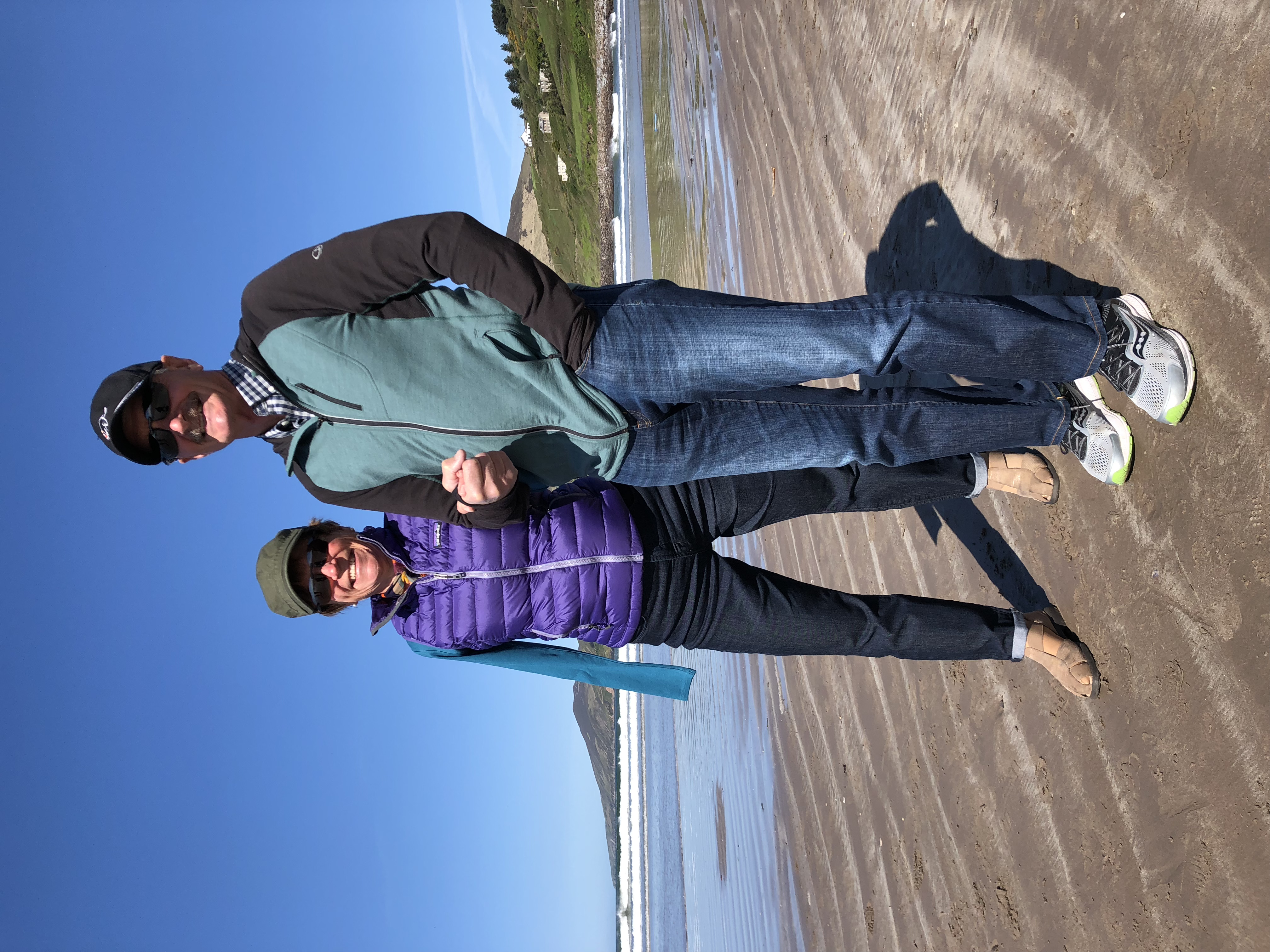 Caucasian couple standing on a sunny beach, wearing jeans and jackets