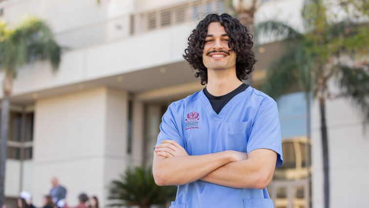 Nito Gil standing with arms crossed wearing blue LLUH scrubs