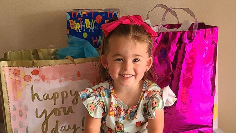 little girl sitting on table with birthday presents and decorations