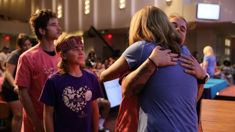A FAMILY EMBRACES A VOLUNTEER WITH A HUG DURING MEMORIAL SERVICE FOR LOST BABIES AND INFANTS