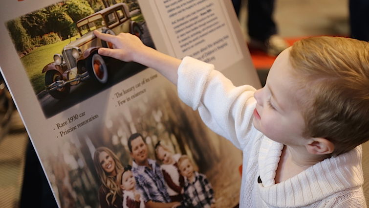 One of the Stuit quadruplets admires the poster promoting the 1930 Cord L29 that was sold at Barrett-Jackson on Jan. 21. The car sold for $300,000, all benefiting LLUCH.