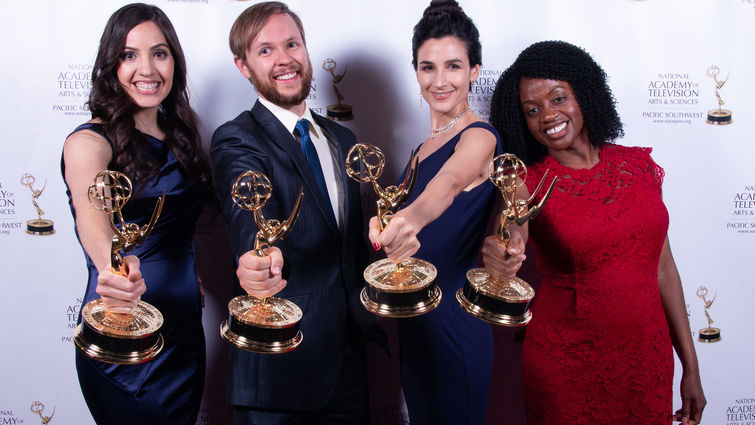 four people hold trophies