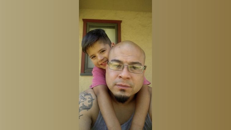 selfie style photo of father with his son leaning on his back