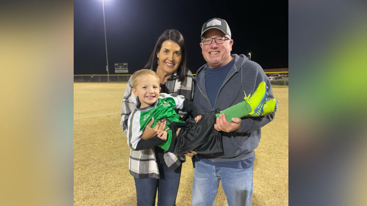 Lisa Cummings and her husband hold their grandson after his soccer match.