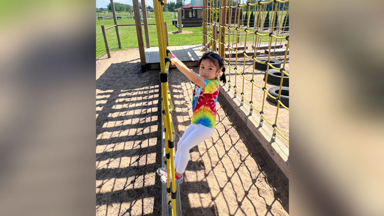 young asian girl climbing on ropes at the park