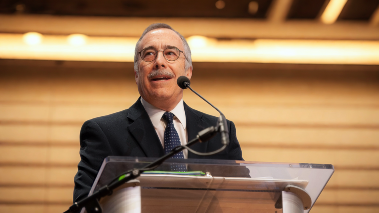 a man is standing in front of a podium with a microphone talking out to an audience 