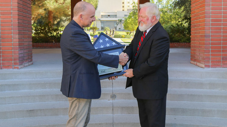 Two male professors shake hand over American flag