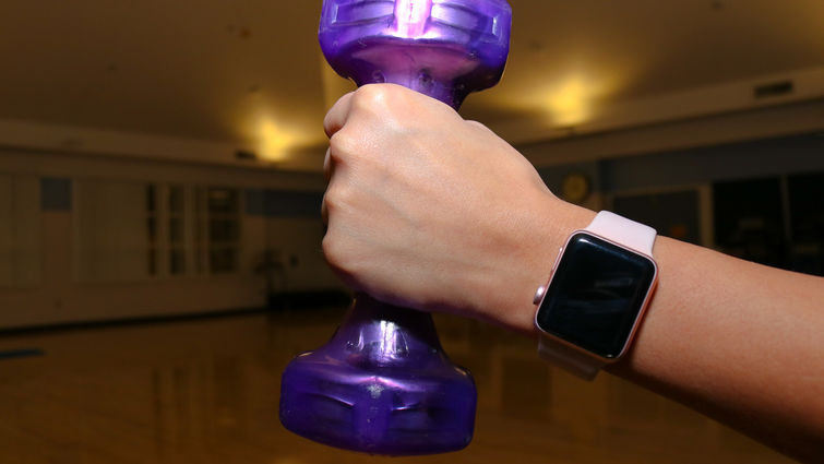 caucasian hand holding small purple dumbbell