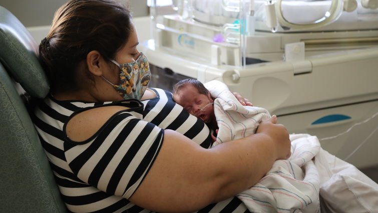 mother sits in the nicu with her small baby