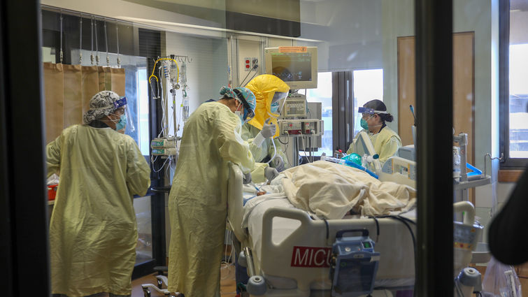 healthcare workers wearing masks and gowns caring for COVID-19 patient