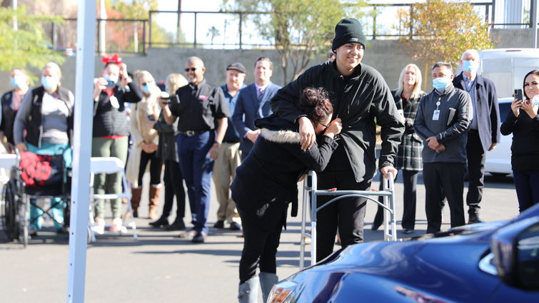 mother and son seeing new car for first time, smiling and emotional