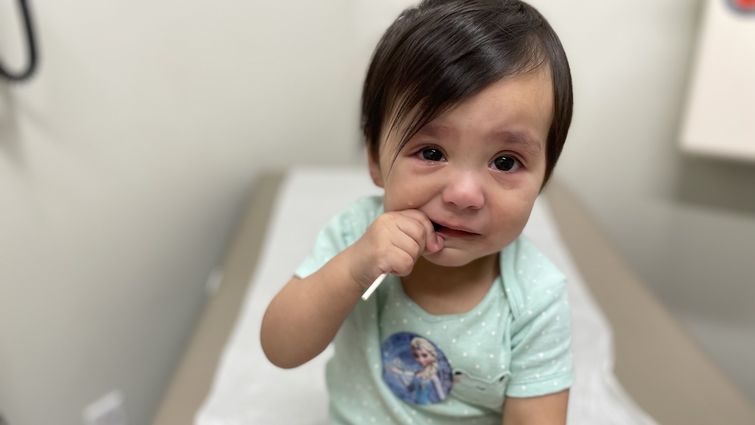 female toddler sitting on doctor's exam table clearly upset