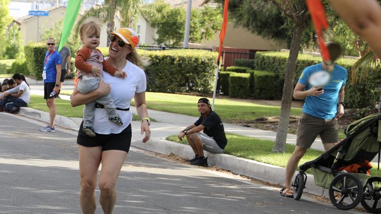 Woman crossing finish line with baby on her hip