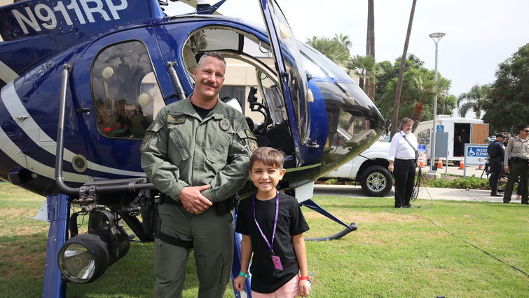 Police officer next to young boy in front of a helicopter