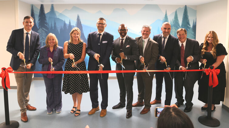 hospital leaders pose while cutting ribbon