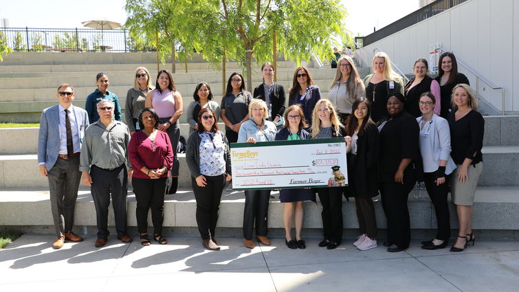 smiling group of male and female hospital staff, administrators, and Farmer Boys representatives pose for photo with presentation check