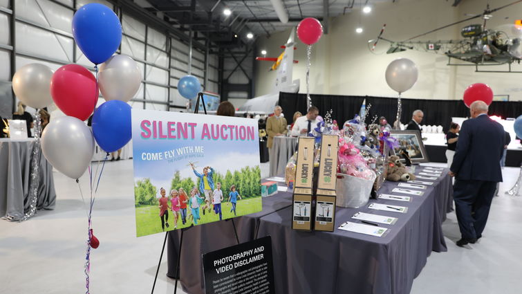 Silent auction sign next to table with a black tablecloth, donned with items displayed at an event