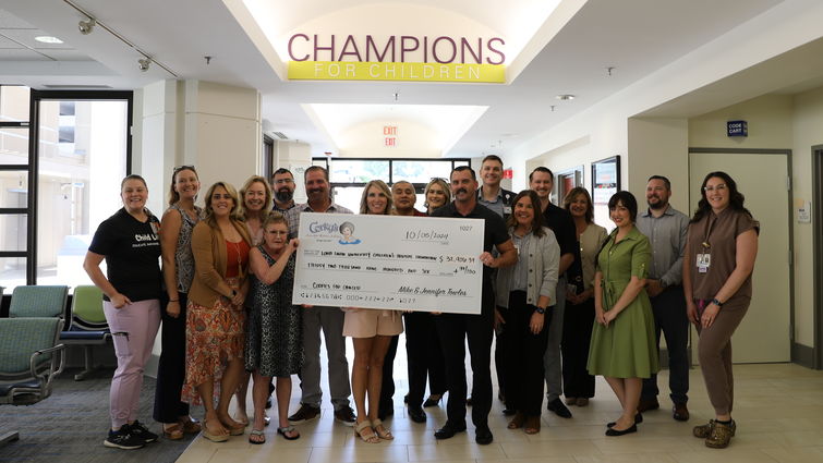 Corky's and Loma Linda University Children's Hospital staff stand together, all smiles, during a check presentation supporting the hospital's mission to provide exceptional care to young patients.