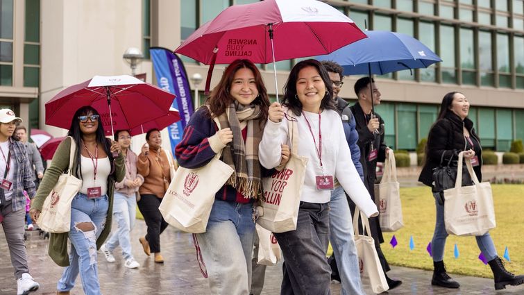 a group pf young adults holding umbrellas walking in the rain