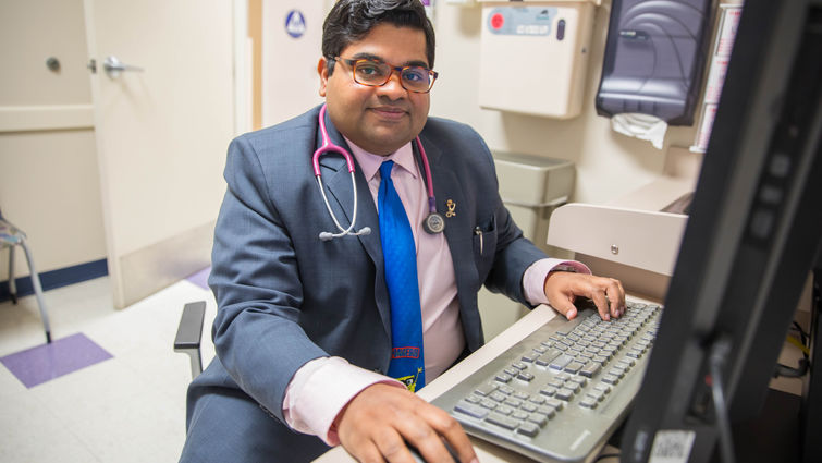 young indian doctor sits in front of computer 