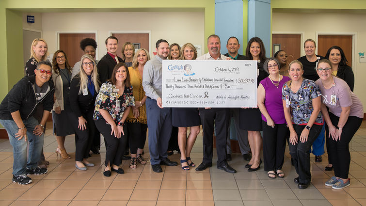 male and female staff and admin from both organizations pose with giant check