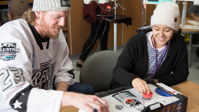 hockey player plays air hockey with teenage female patient