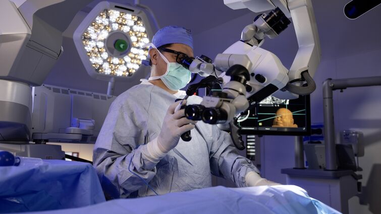 A doctor looks through microscope during surgery 