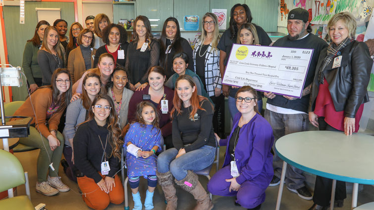 hospital staff, store staff and patient pose with check