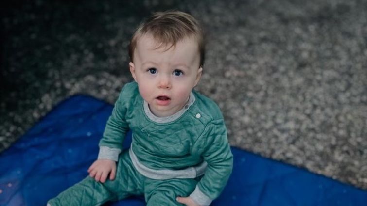 one year old baby Oliver Bonds sits on blue blanket and looks at the camera