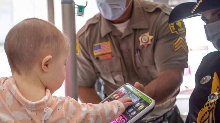 baby plays with toy held by sheriff's deputy