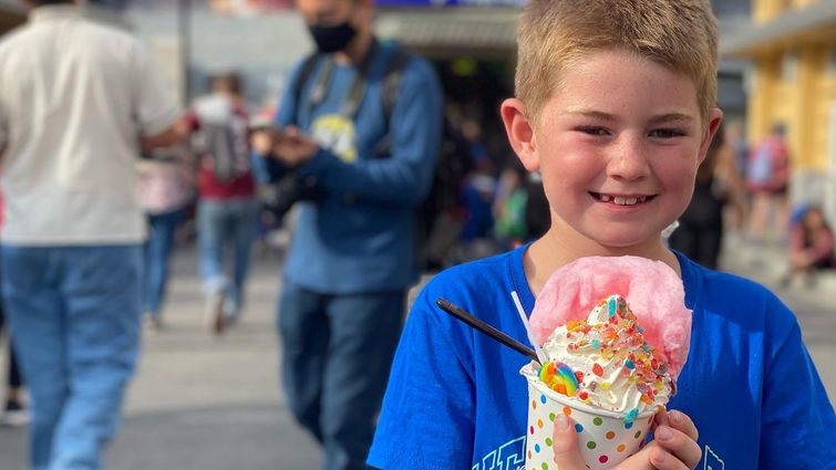 young Caucasian boy in blue t-shirt holding a candy ice cream sundae