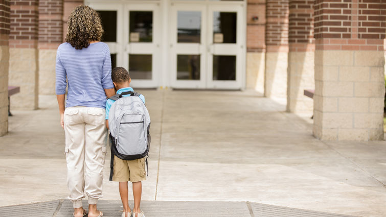 Nervous boy. First day of school. Holds on to mom. stock photo