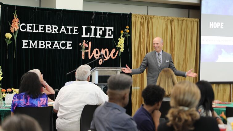 A man in a grey suit stands in front of the crowd and gives a sermon about embracing hope